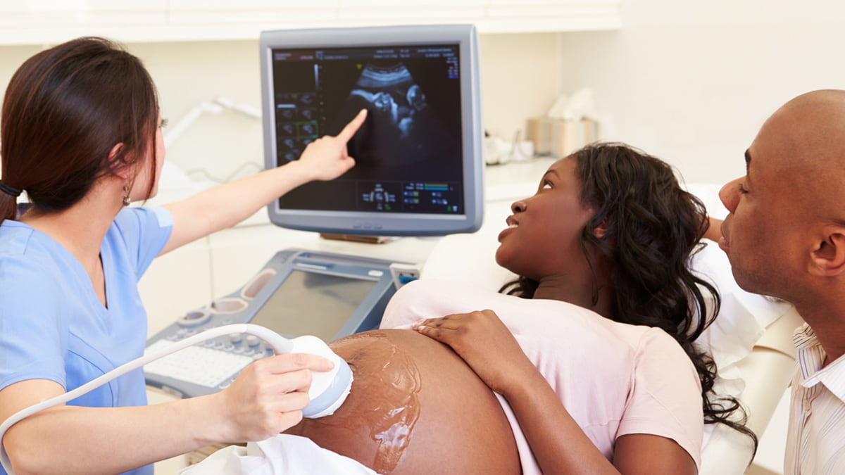 Profesional médico haciéndole una ecografía a una mujer embarazada.