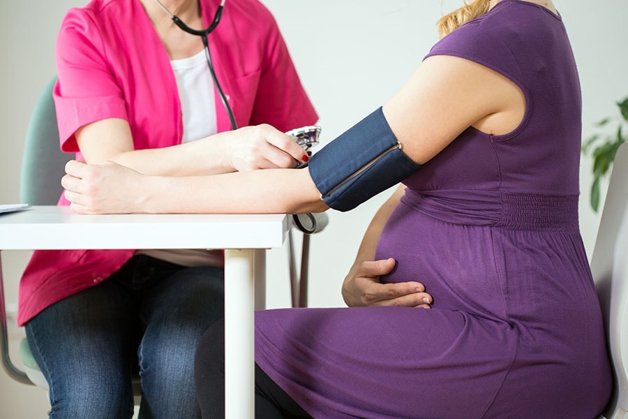 A doctor measuring a pregnant woman's blood pressure.