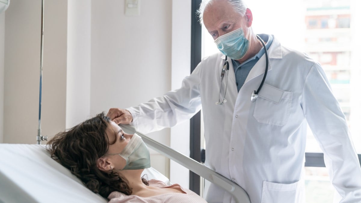Foto de una paciente con cáncer de mama en una cama de hospital hablando con su médico