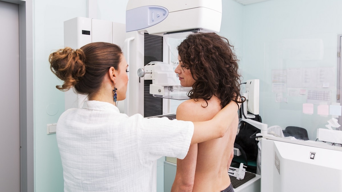 a nurse positioning a woman for a mammogram