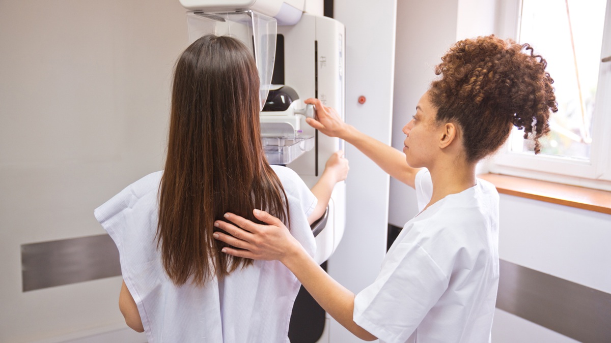 A nurse helps a woman get a mammogram