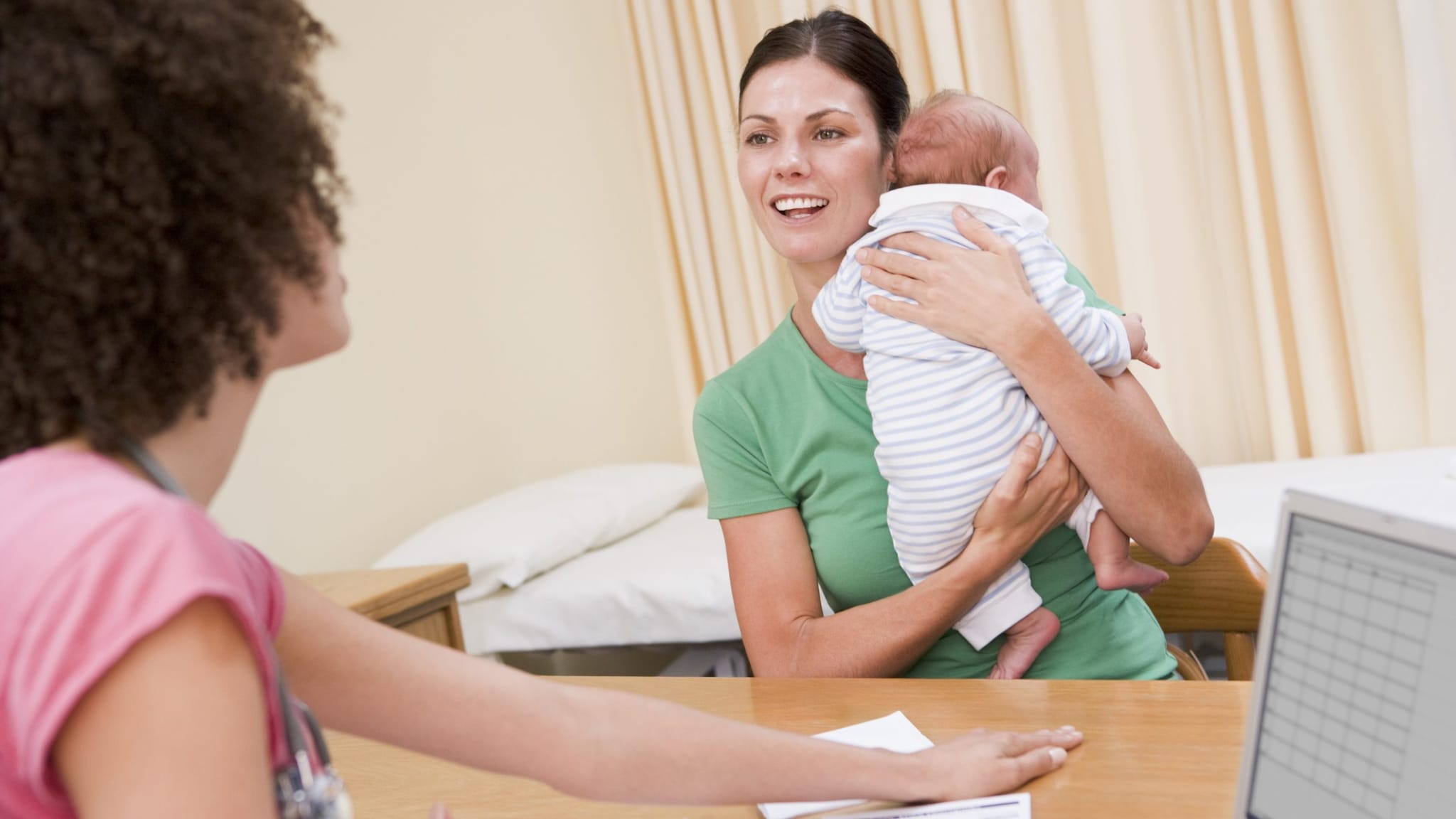 A mother with infant consulting with a healthcare professional.