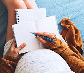 A pregnant woman taking notes.