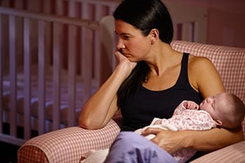 Depressed mother holding her sleeping infant.
