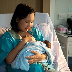 A mother breastfeeding in a hospital bed