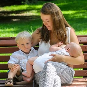 A breastfeeding mother sitting on a park bench