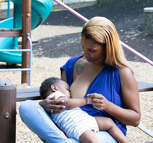 A woman breastfeeding her child at a playground