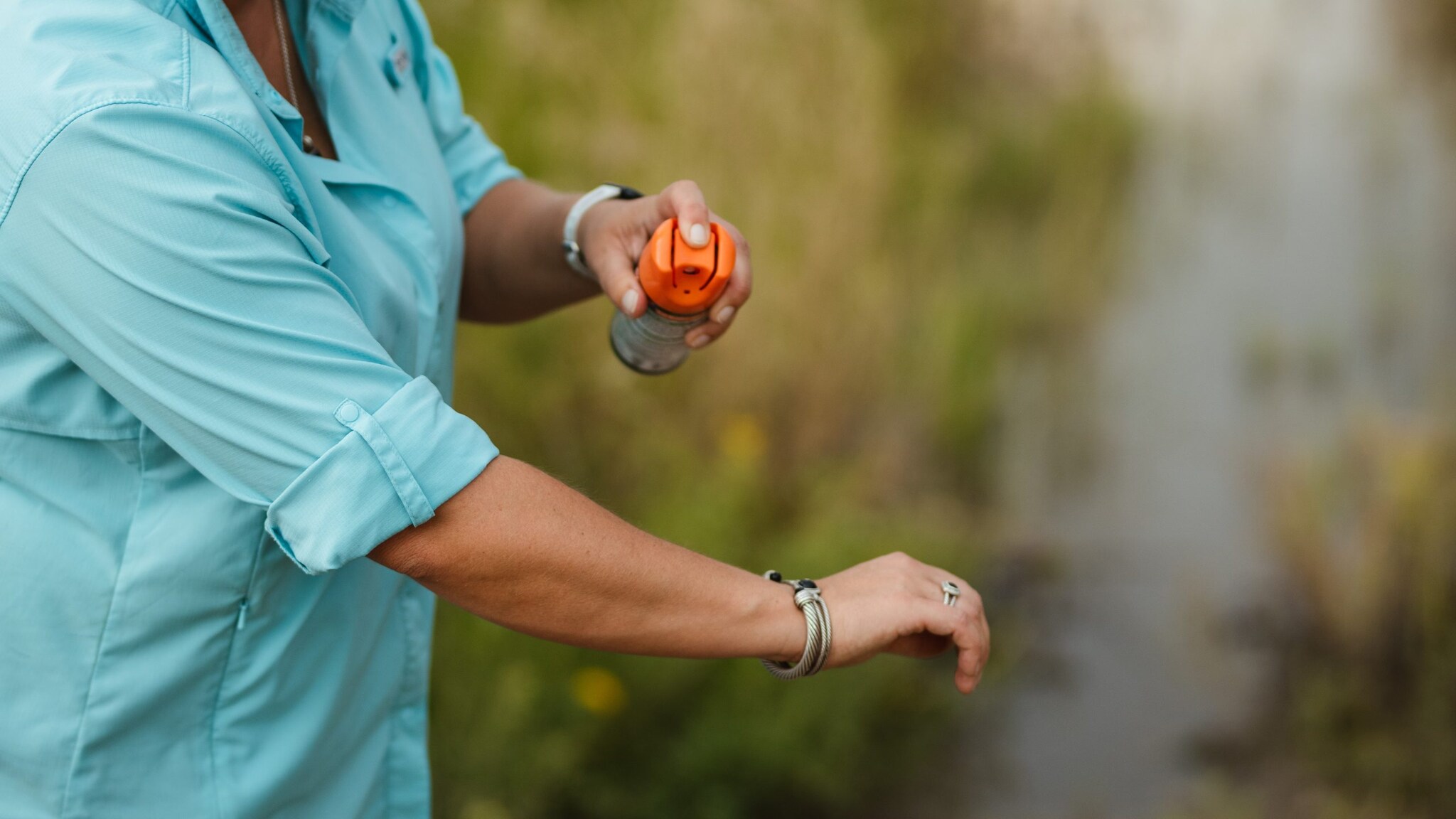Woman applying insect repellant on her arm.