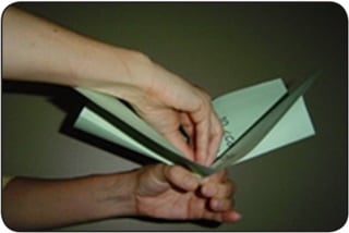 Una persona dobla hojas de papel verde para formar un repollo de papel