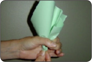 Una persona dobla hojas de papel verde para formar un repollo de papel