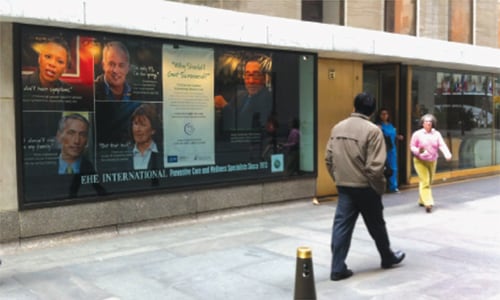 Photo of the No Excuses poster displayed in a window at Rockefeller Center in New York City