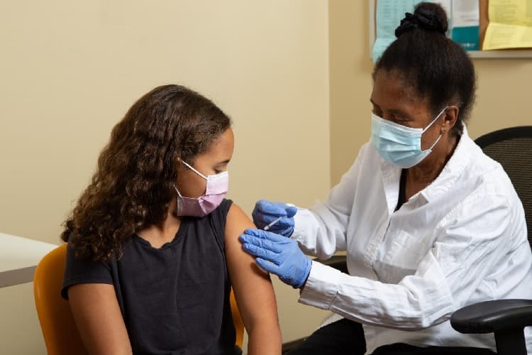 A health care professional administering a vaccine to a girl.