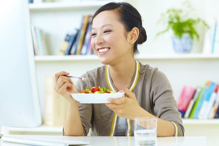 Photo of a young Asian woman eating a salad