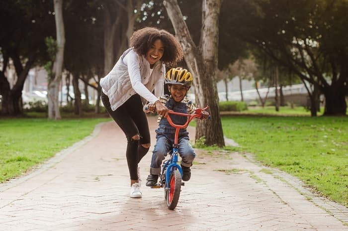 Photo of a woman teaching son to ride a bicycle at a park