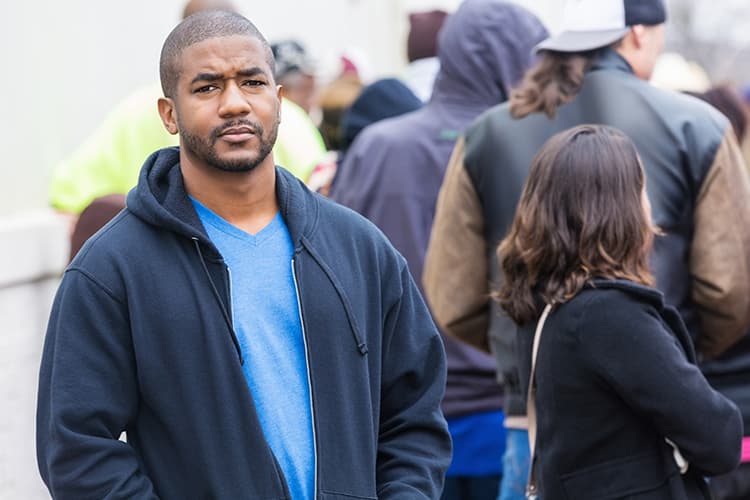 Photo of an African American man standing on a crowded sidewalk