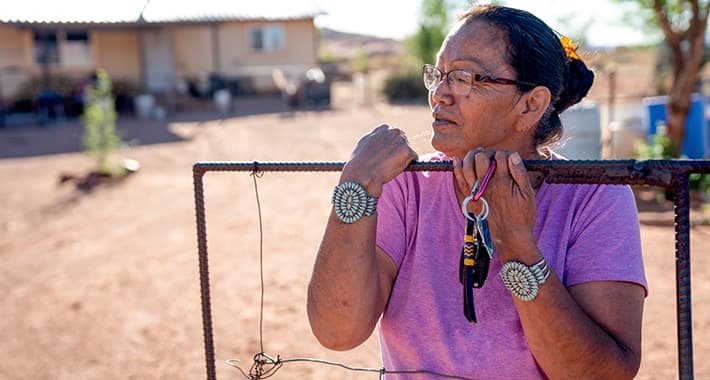 A Navajo woman standing by the gate of her home in Monument Valley, Arizona.