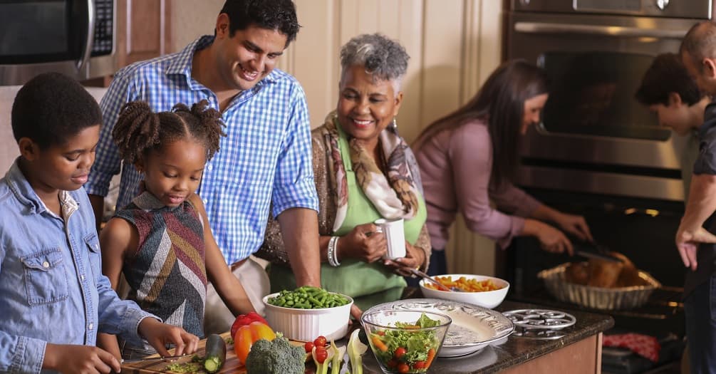 Multi-ethnic family members prepare Thanksgiving dinner in grandmother's kitchen