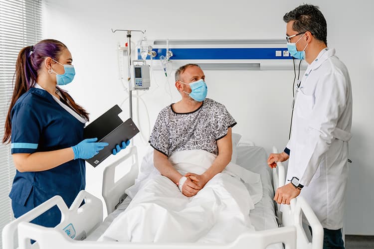 Photo of a man in a hospital talking to his doctor and nurse