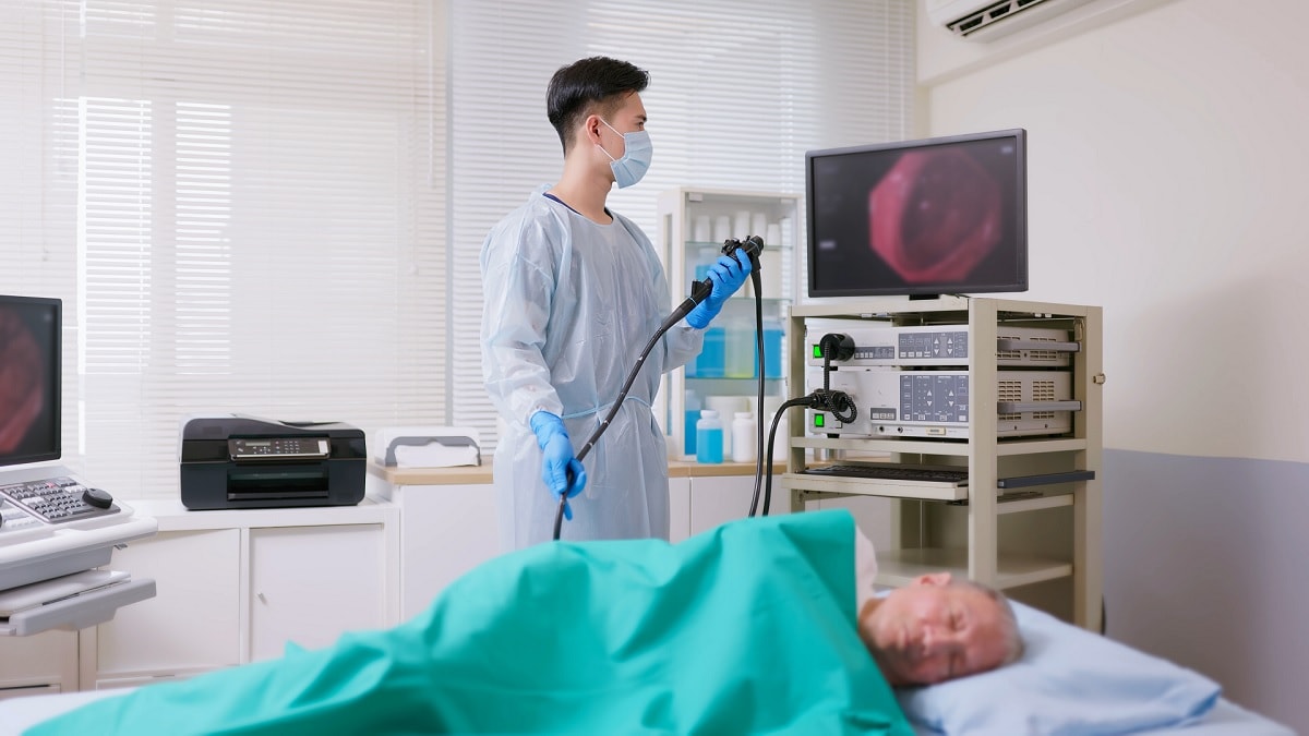 A doctor performs a colonoscopy on an older man