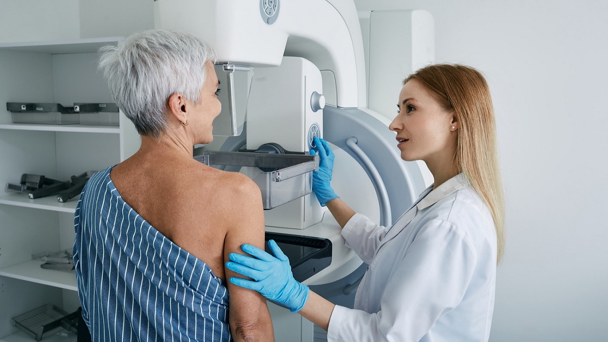 A nurse positions an older woman for a mammogram