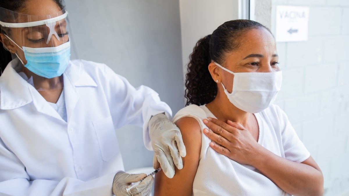 Una profesional de salud vacunando a su paciente contra el COVID-19