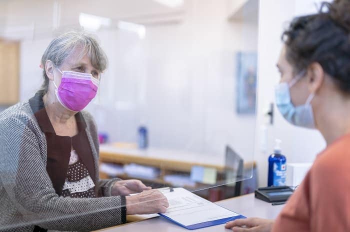 Photo of a receptionist helping patient fill out a form at medical clinic