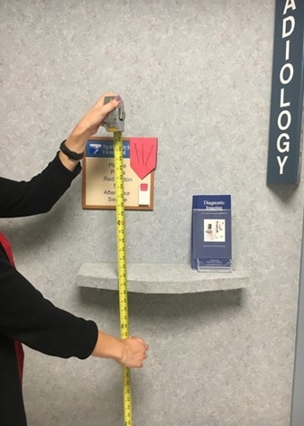 A person measures the height of a sign in a mammography clinic