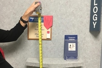 Photo of a person measuring the height of a sign in a mammography clinic