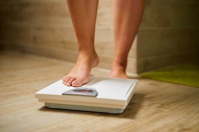 Photo of a woman stepping onto a bathroom scale