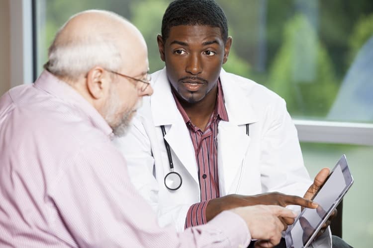 Photo of a doctor explaining treatment to a senior man on digital table