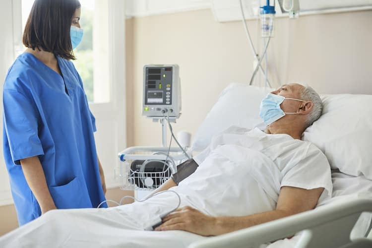 Foto de un paciente de cáncer en una cama de hospital con su cirujana
