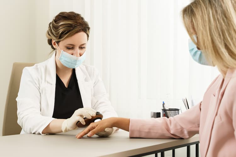 Photo of a doctor examining a mole on a woman's hand