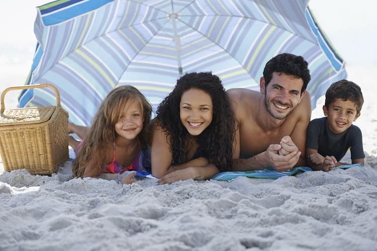 Photo of a family under a large umbrella on the beach