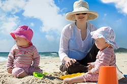 Photo of a woman and her children wearing hats and long sleeved shirts.