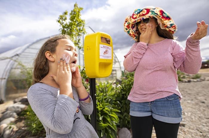 Elizabeth and Gabriel Thompson apply sunscreen from the dispenser at Urban Roots Teaching Farm in Reno, Nevada