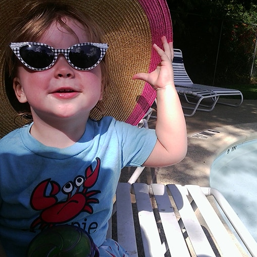 Girl showing off her sun-safe style at the pool with a wide-brimmed hat and sunglasses.