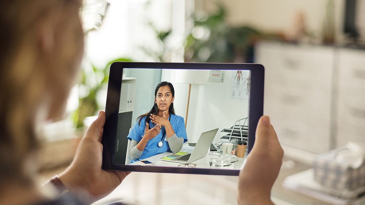 Woman on a telehealth meeting with a medical professional, viewing on her tablet.