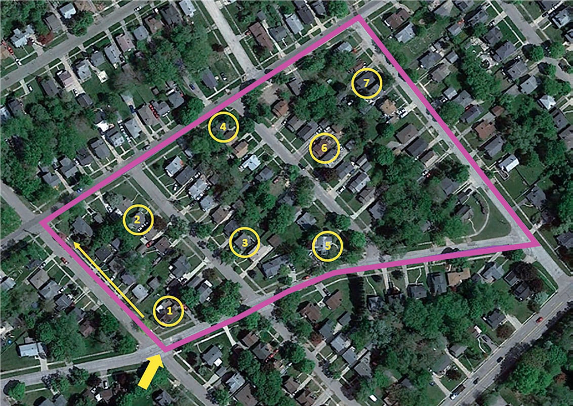 Aerial view of a neighborhood outlined in pink. Seven households are selected randomly.