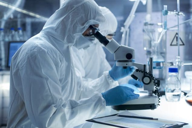 Image of scientist in lab, looking into a microscope