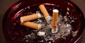 Image of an ashtray, containing four used cigarette butts and ashes