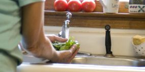 Image of person in a kitchen, washing vegetables with tap water