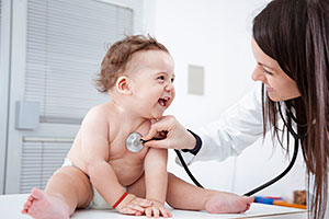 Laughing baby examined by female doctor.