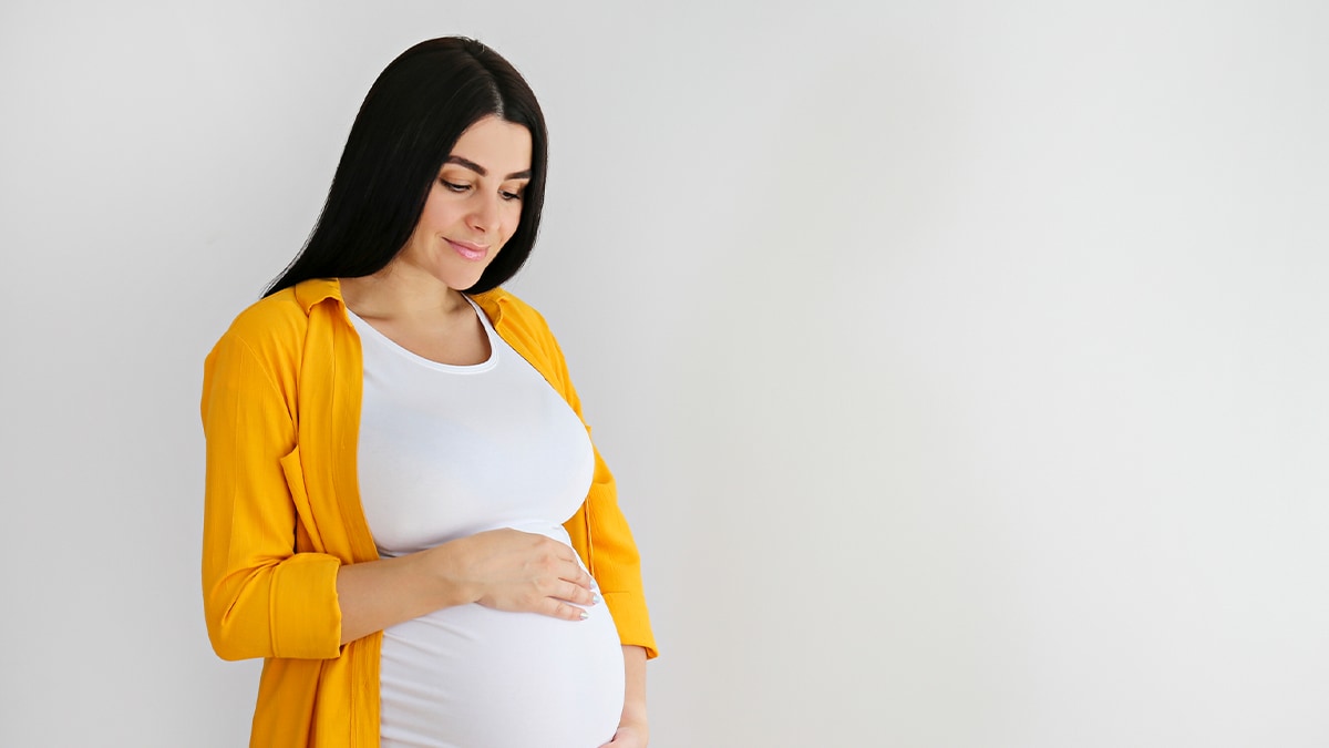 Pregnant woman with yellow shirt holding belly