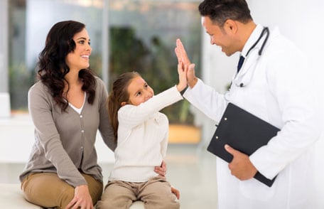 Mother with young daughter who is high-fiving doctor