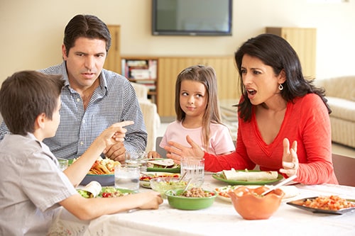 Family sitting at dinner table arguing..