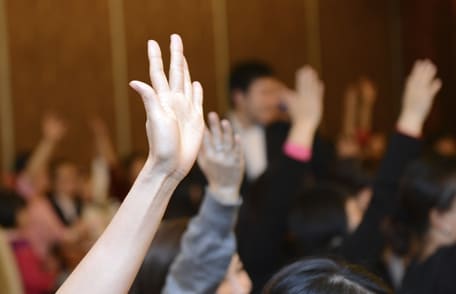 Photo of hands being raised at a meeting