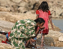 Two Southeast Asian women washing their hands in a river