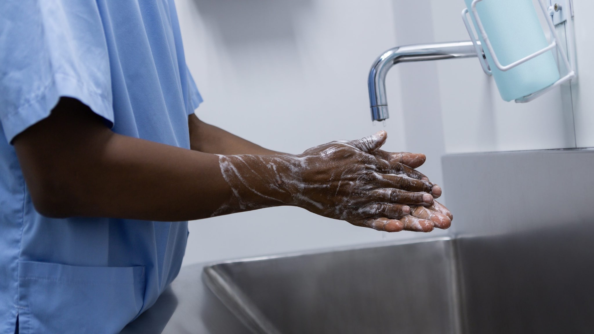 Healthcare provider washing his hands with soap and water.