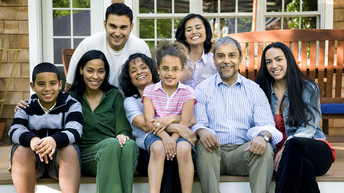 A large family seated on the steps of their home.