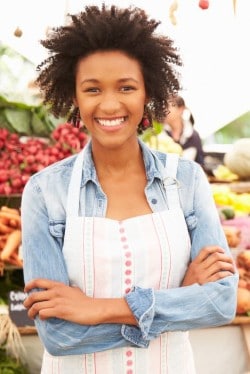 Woman Standing in Front of Veggie Stand